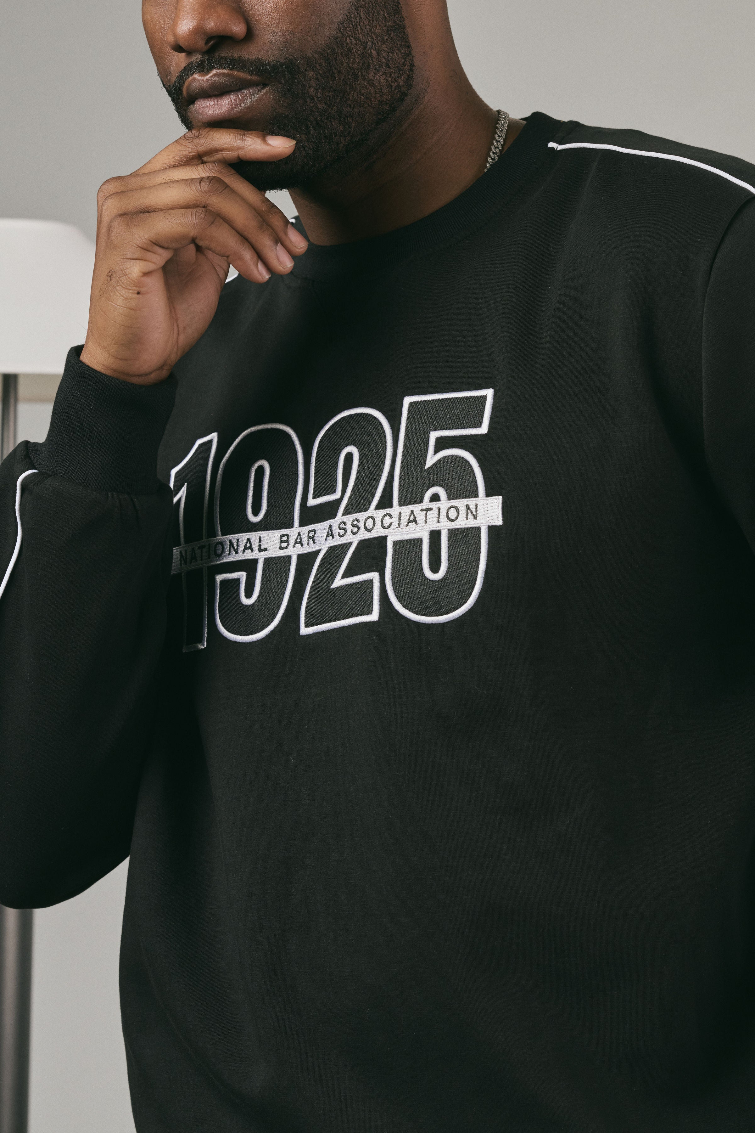 Close up of a man wearing a black sweatshirt with '1925 National Bar Association' text.