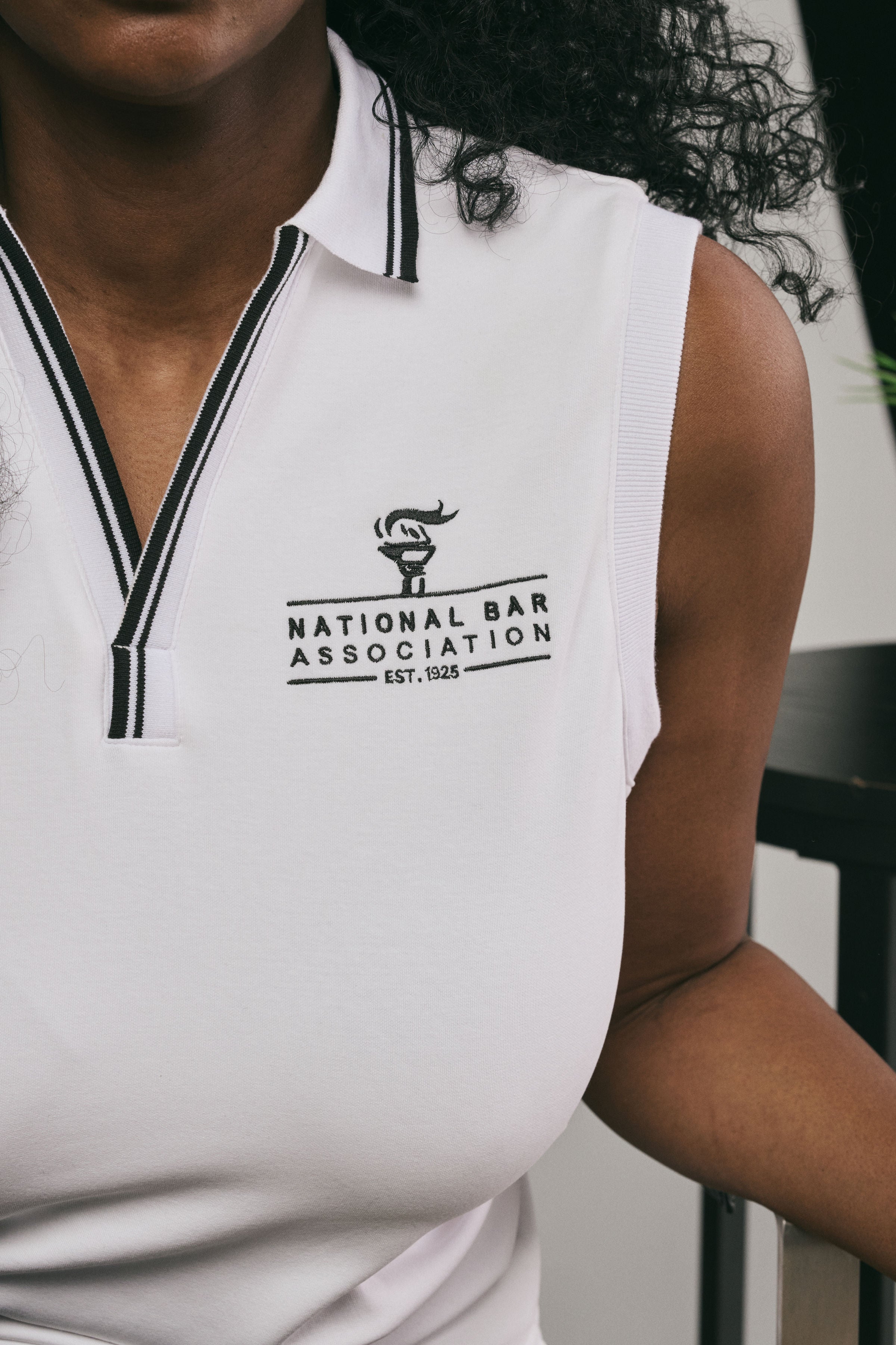 White sleeveless shirt with National Bar Association logo worn by a person.
