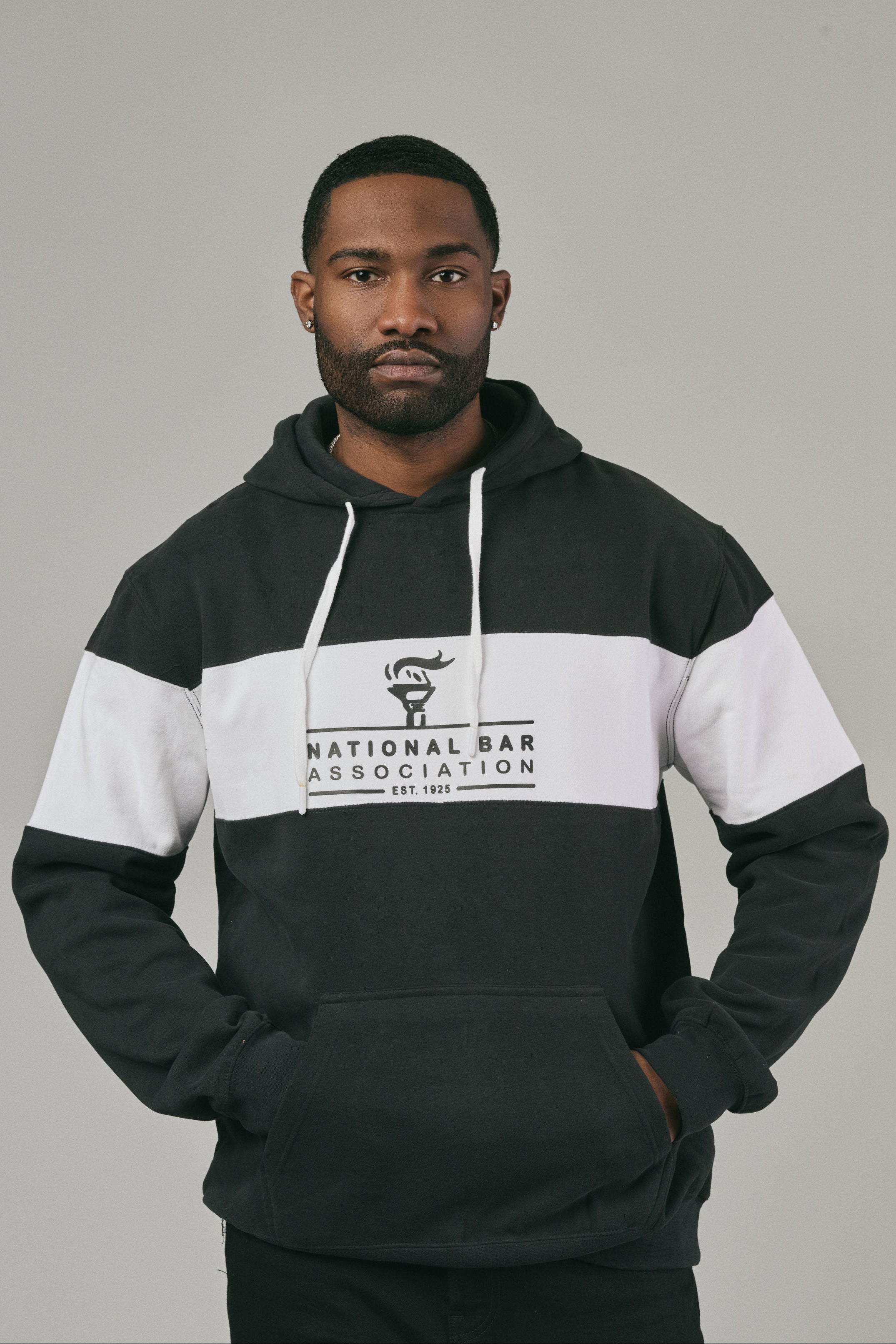 Man wearing a black and white hoodie with 'National Bar Association' logo on a grey background
