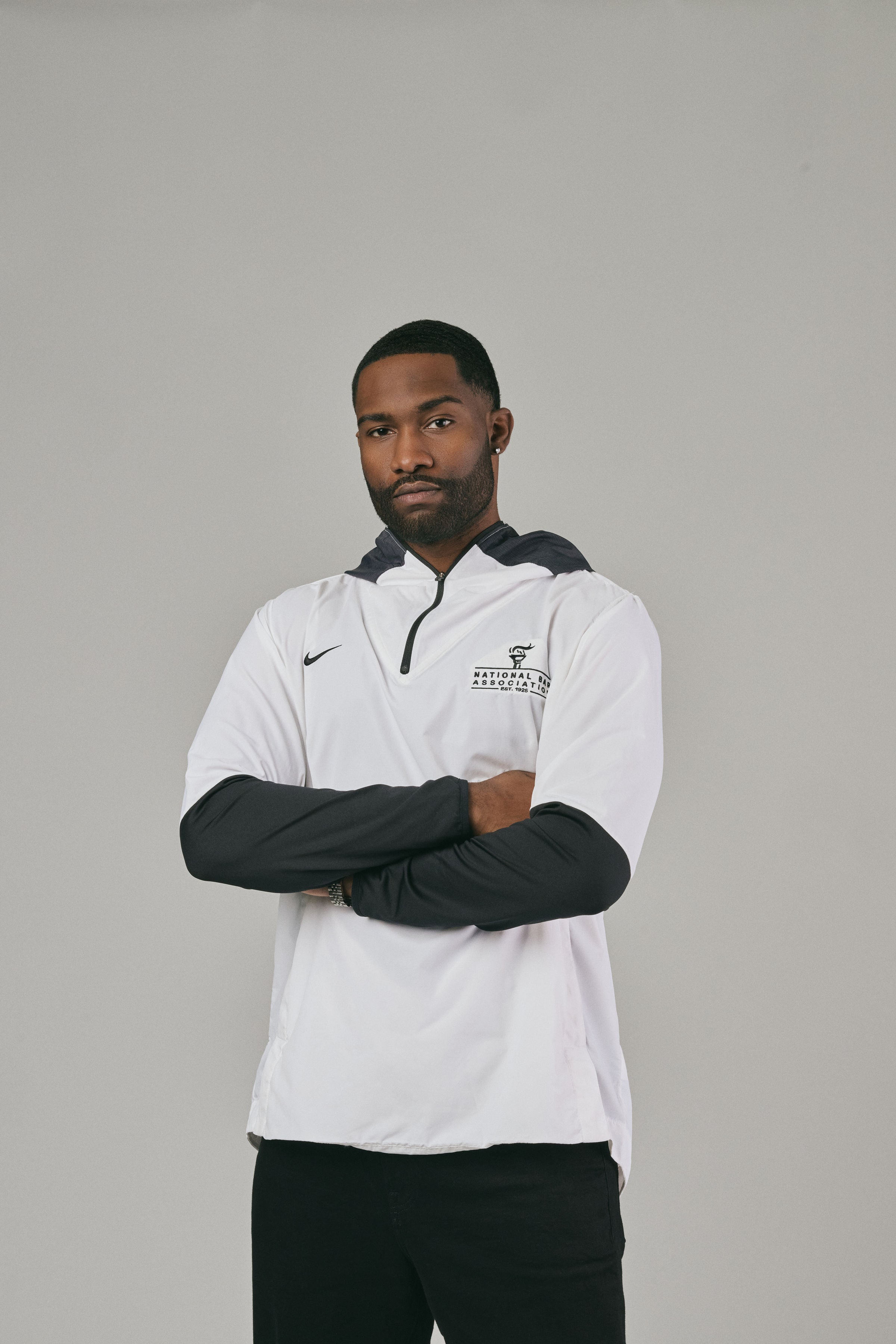 Man wearing a white and black jacket with a logo on a grey background