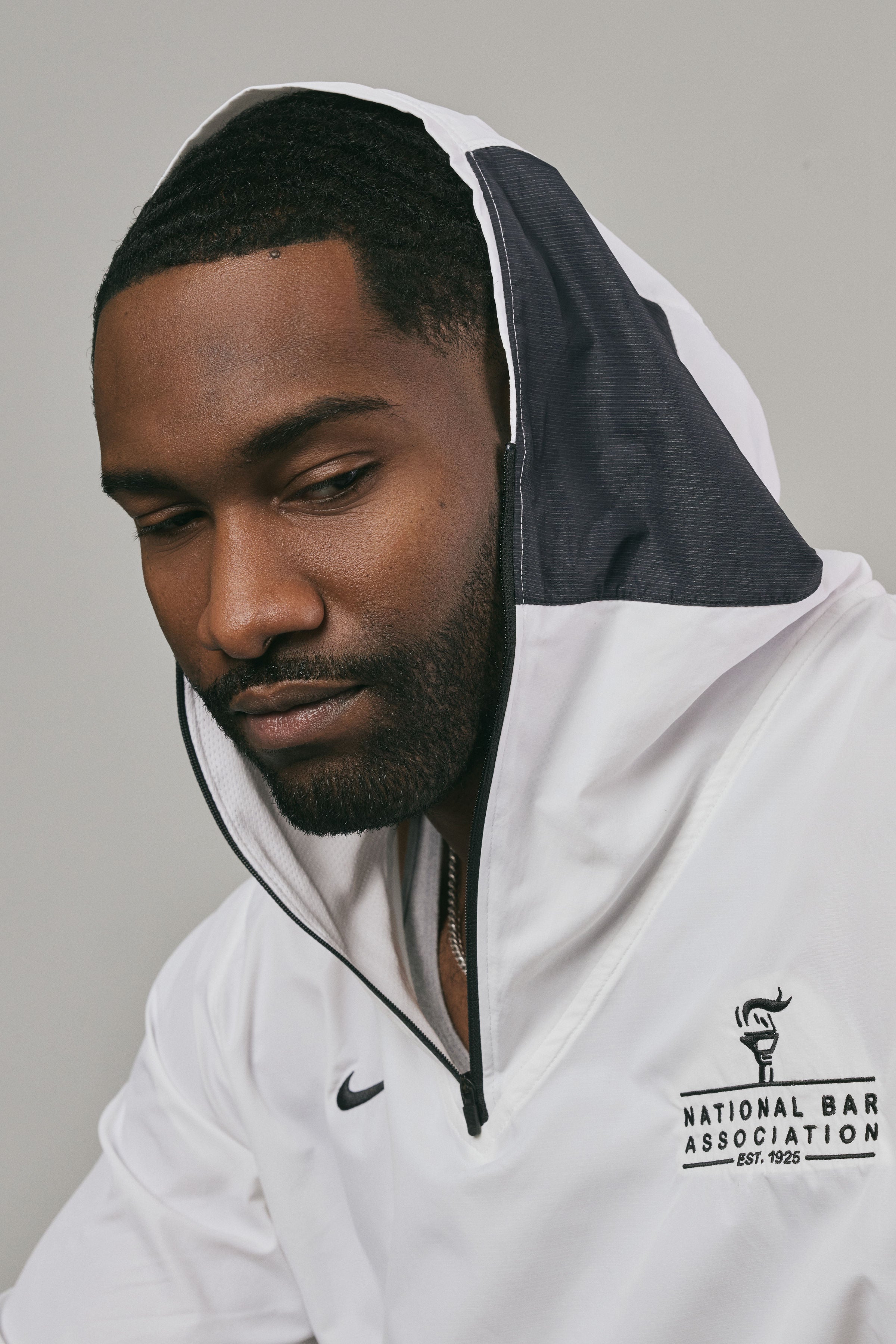Man wearing a white hoodie with a logo on a grey background