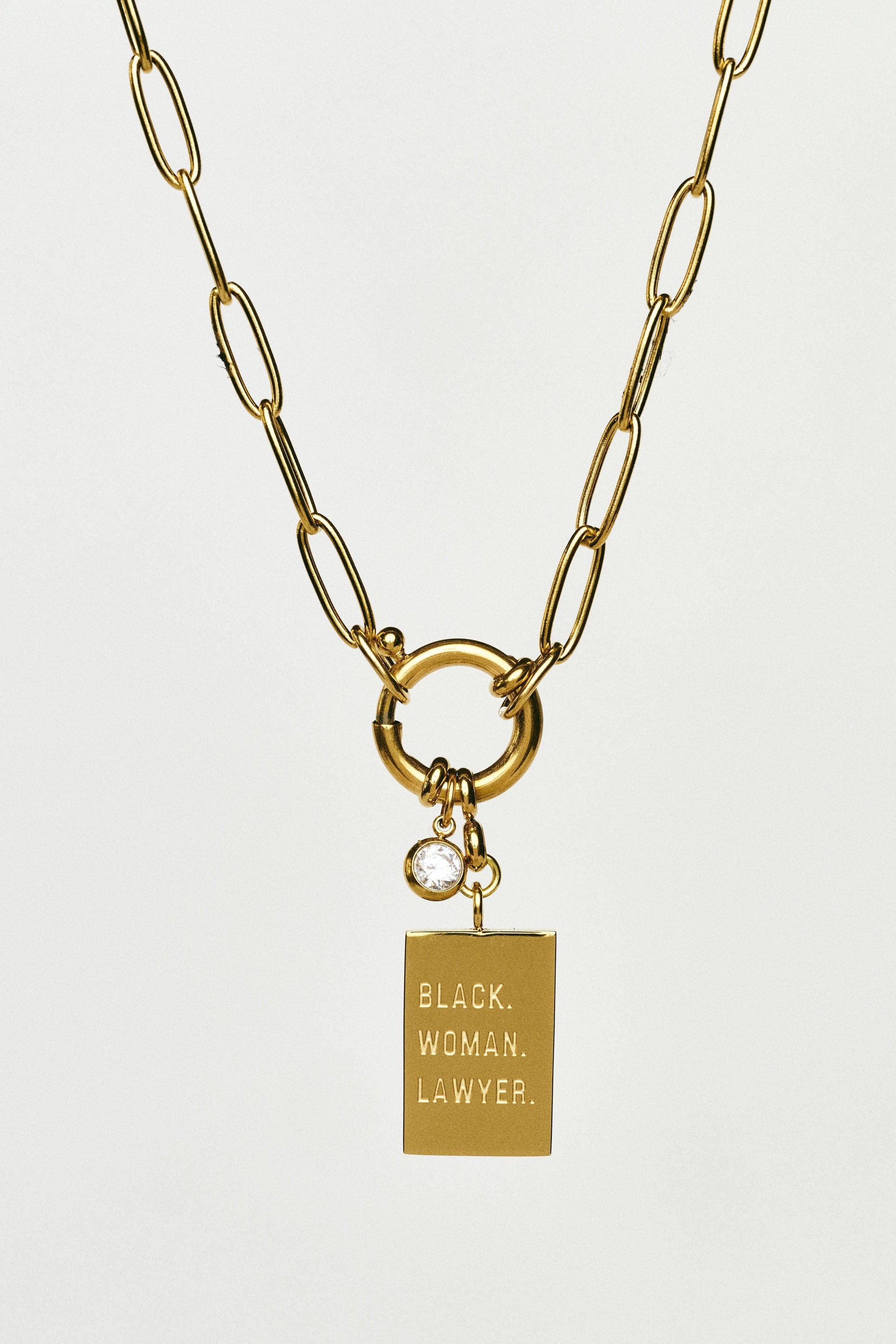 Gold necklace with a pendant that reads 'Black Woman Lawyer' on a white background