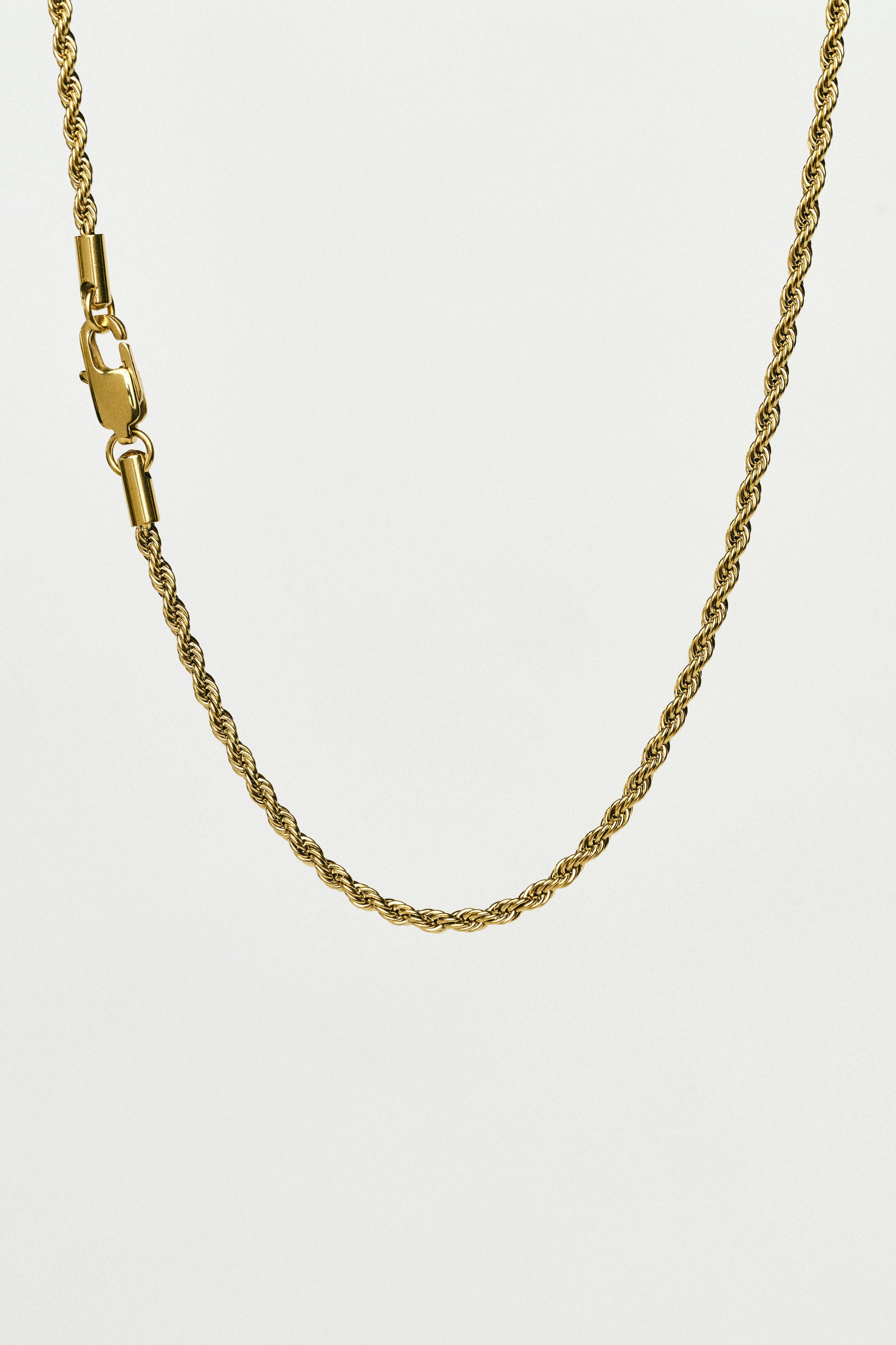 Gold rope chain necklace on a white background