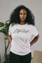 Woman wearing a white t-shirt with 'Call Your Lawyer' text in a home setting