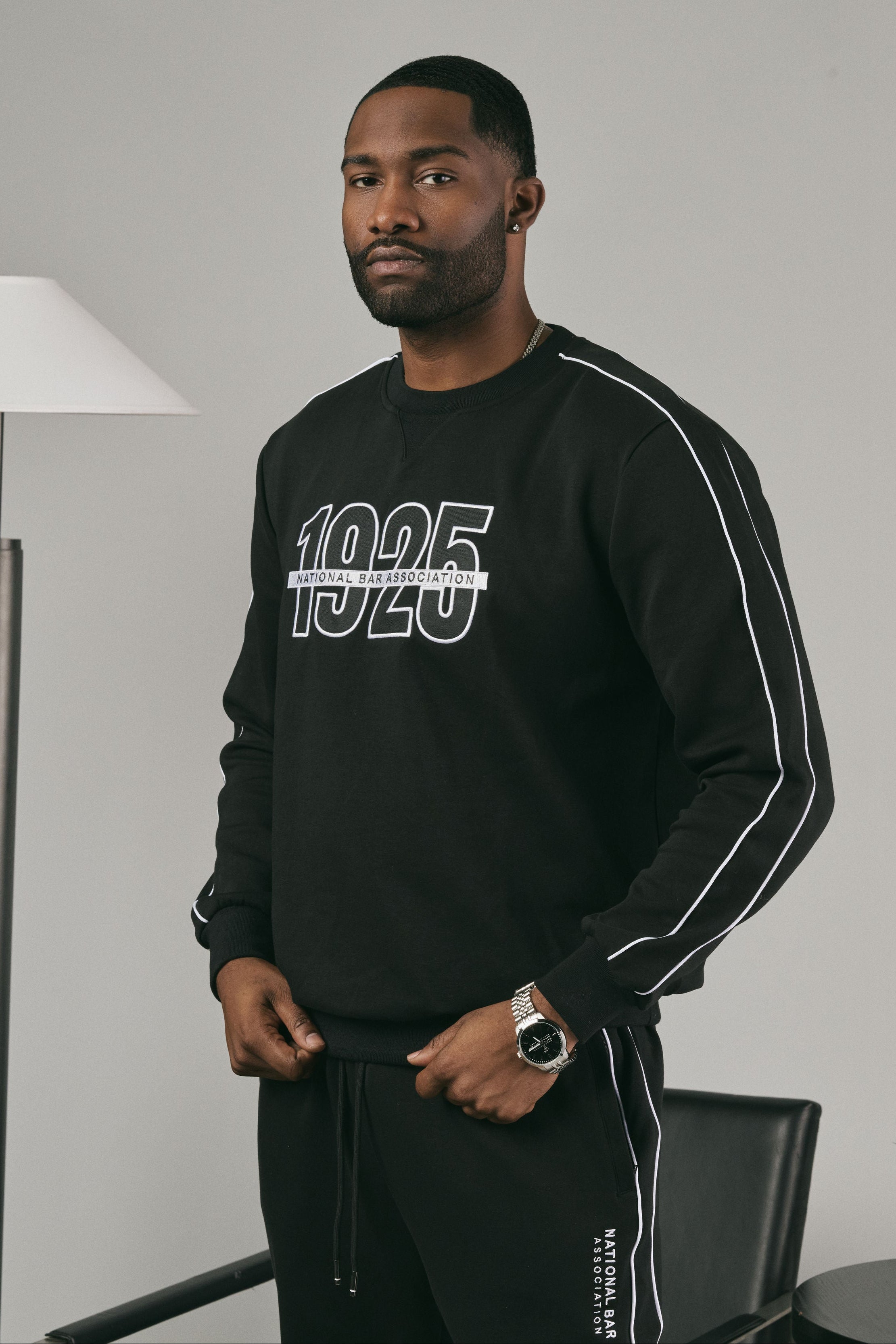 Man wearing a black sweatshirt with '1925' on it in an indoor setting.
