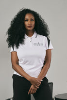 Woman wearing a white polo shirt with a logo on a grey background