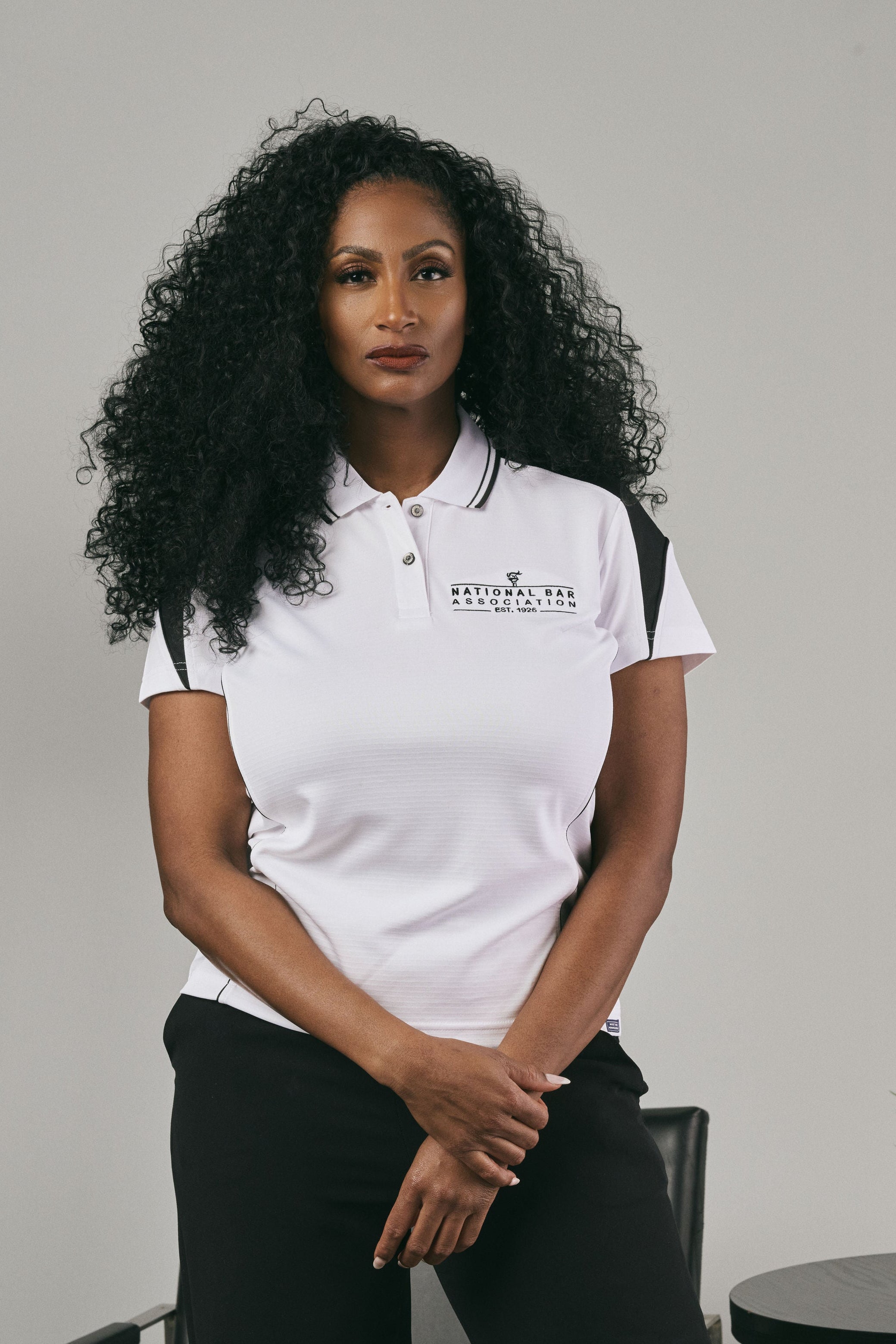 Woman wearing a white polo shirt with a logo on a grey background