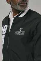 Close up of a man wearing a black jacket with 'National Bar Association' logo and text on a grey background