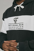 Close up of a person wearing a black and white hoodie with 'National Bar Association' logo on a grey background