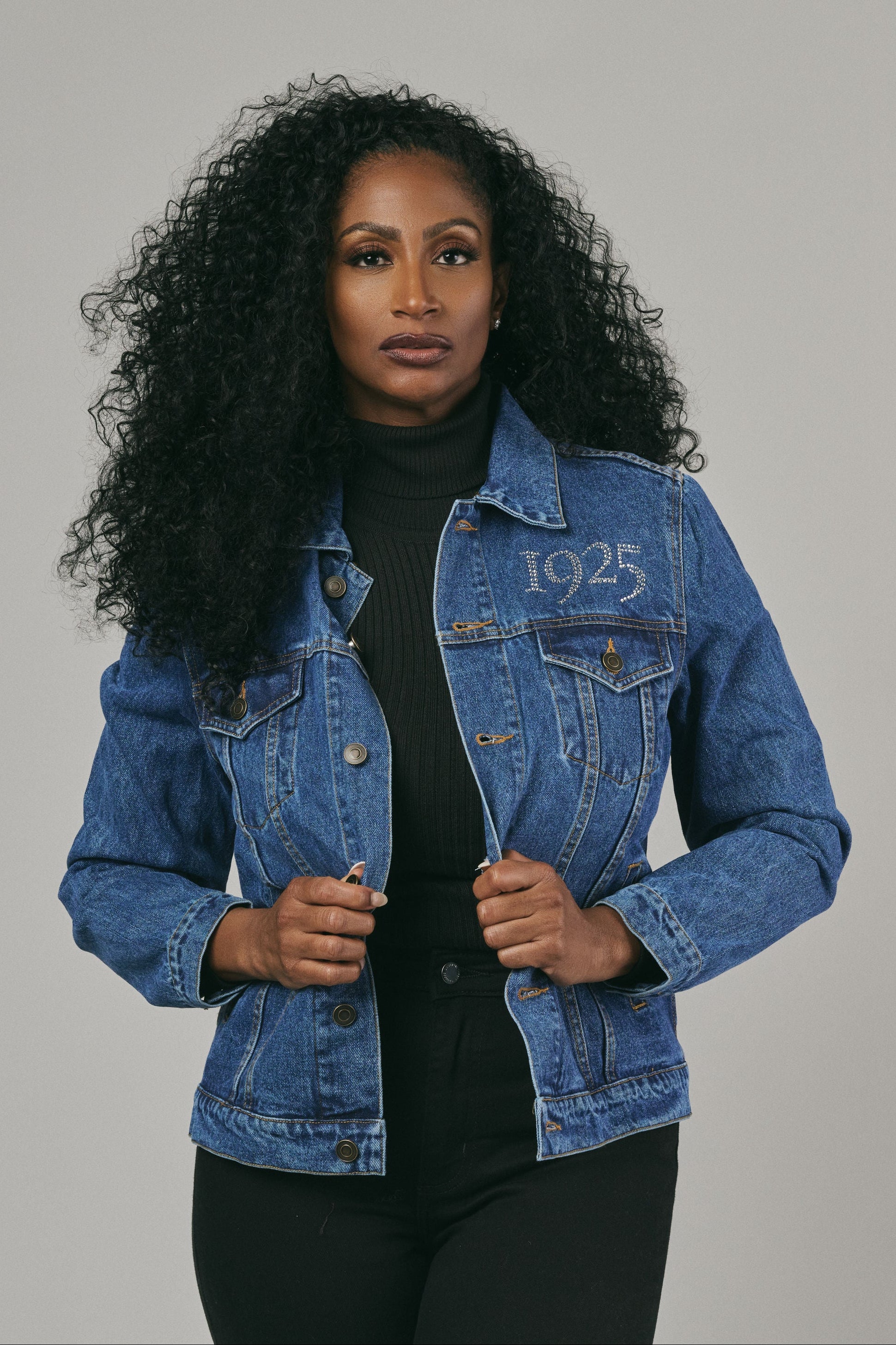 Woman wearing a blue denim jacket on a grey background