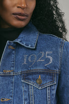 Close-up of a person wearing a blue denim jacket with '1925' embroidery.