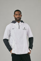 Man wearing a white and black jacket with a logo on a grey background