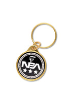 Golden keychain with a black and white 'NBA' logo on a white background