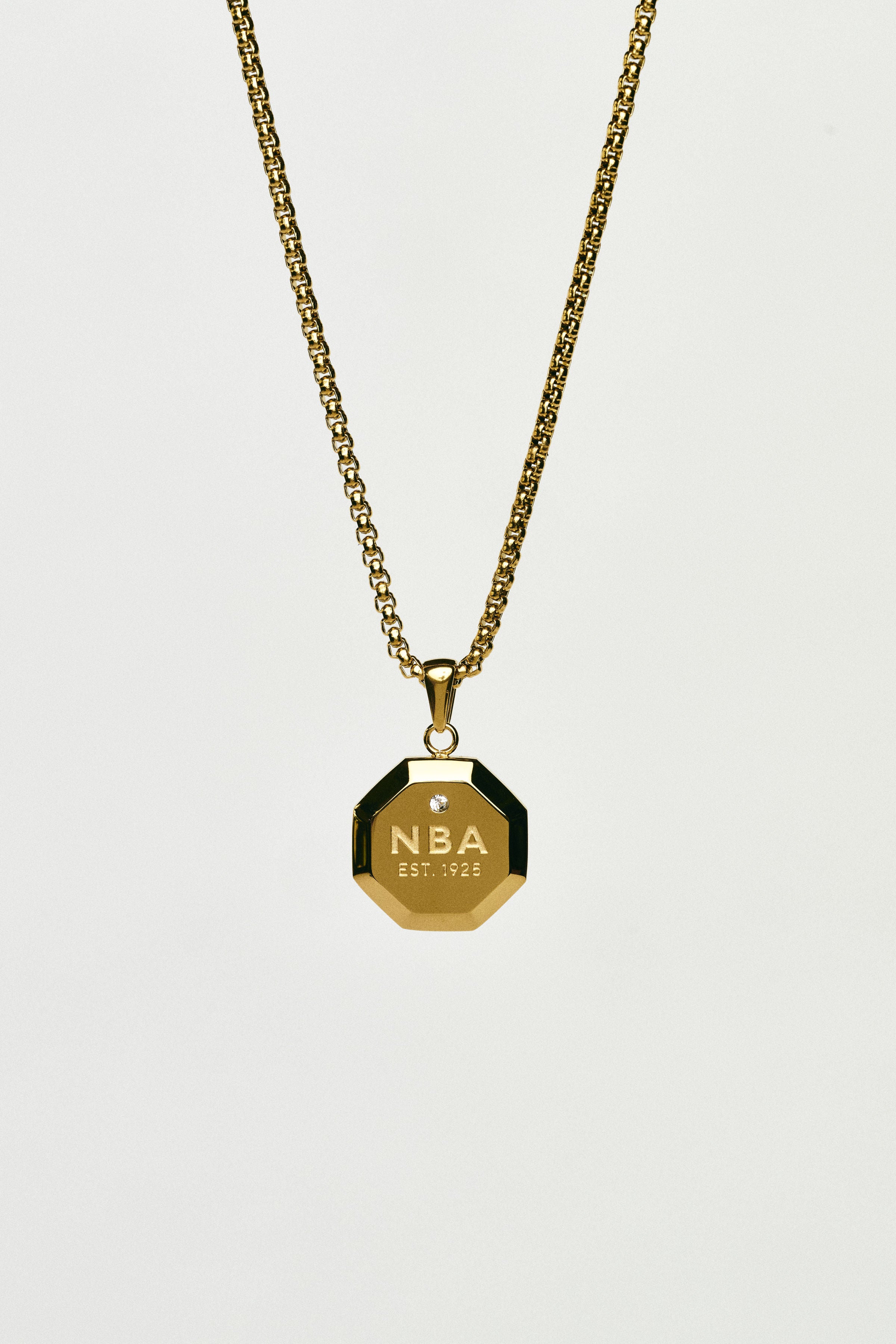 Gold necklace with an NBA pendant on a light grey background