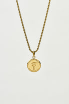 Gold necklace with a round pendant on a light grey background