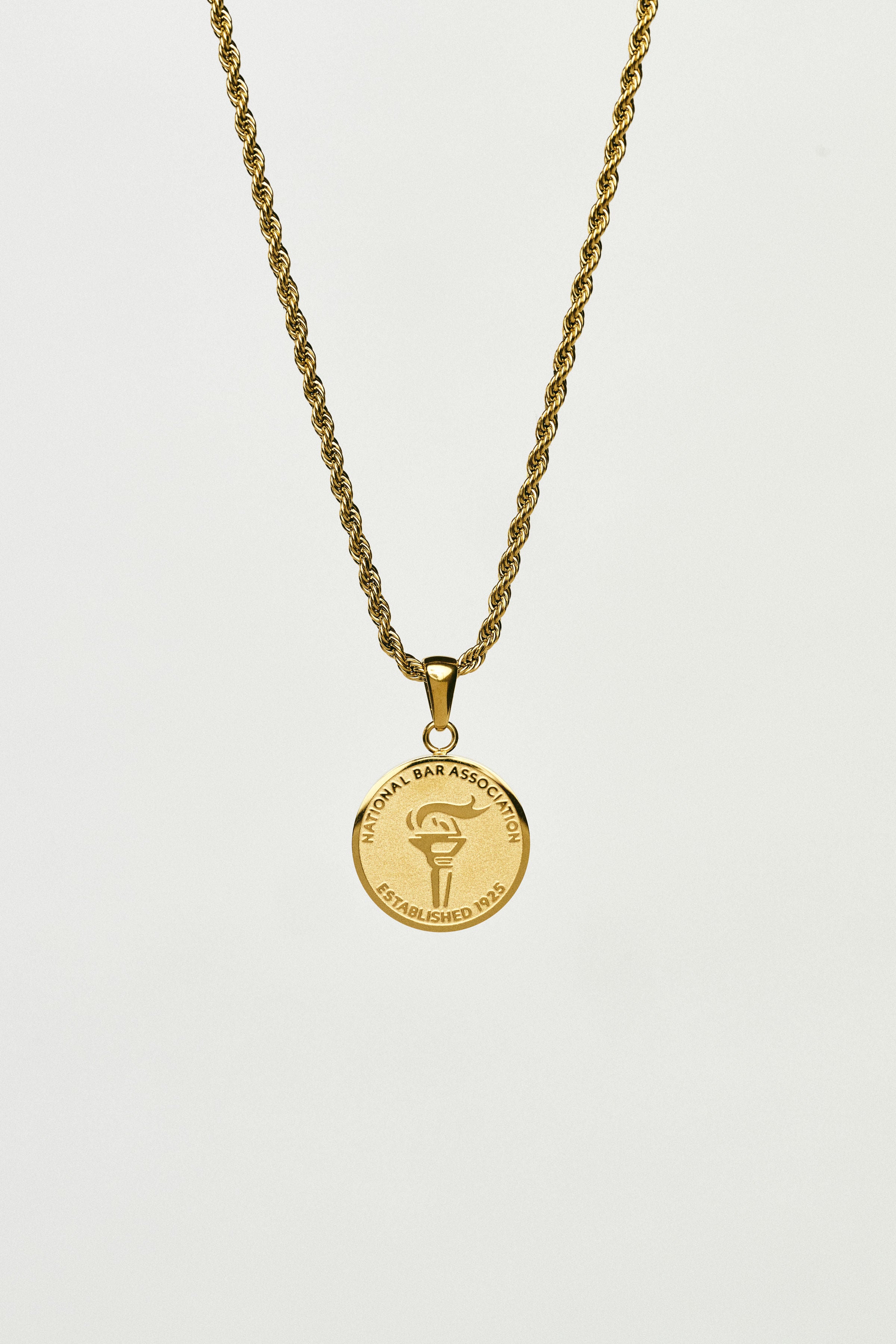 Gold necklace with a round pendant on a light grey background
