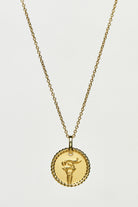 Gold necklace with a round pendant on a light grey background