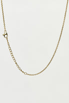 Gold chain necklace on a light grey background