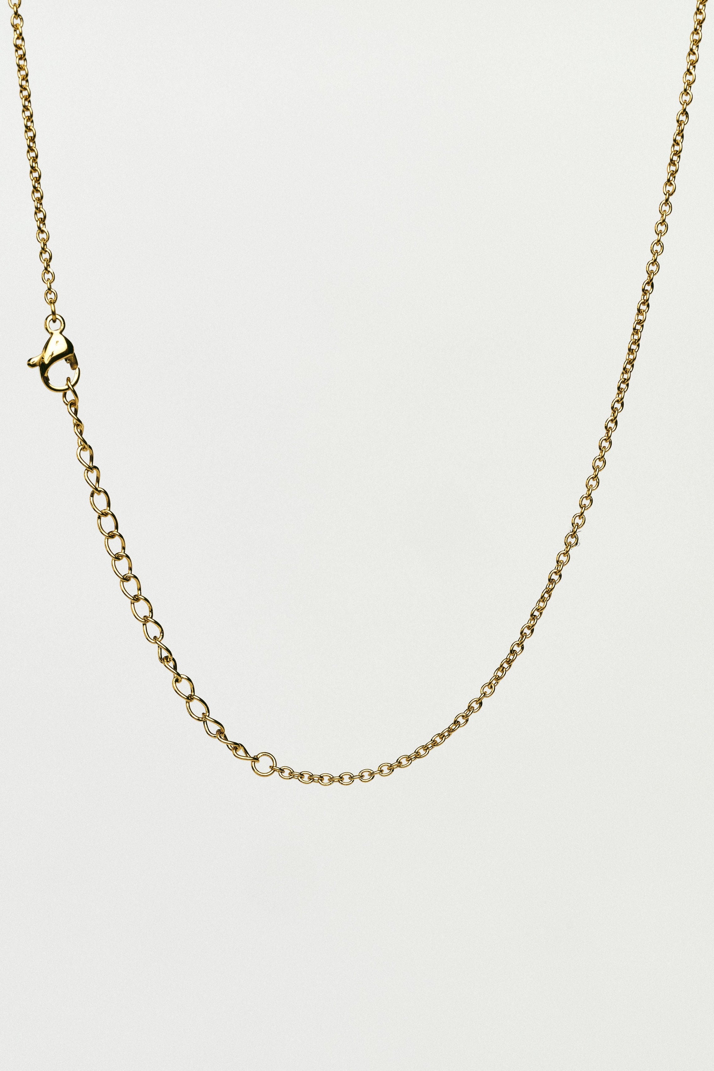 Gold chain necklace on a light grey background