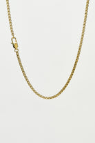 Gold chain necklace on a light grey background