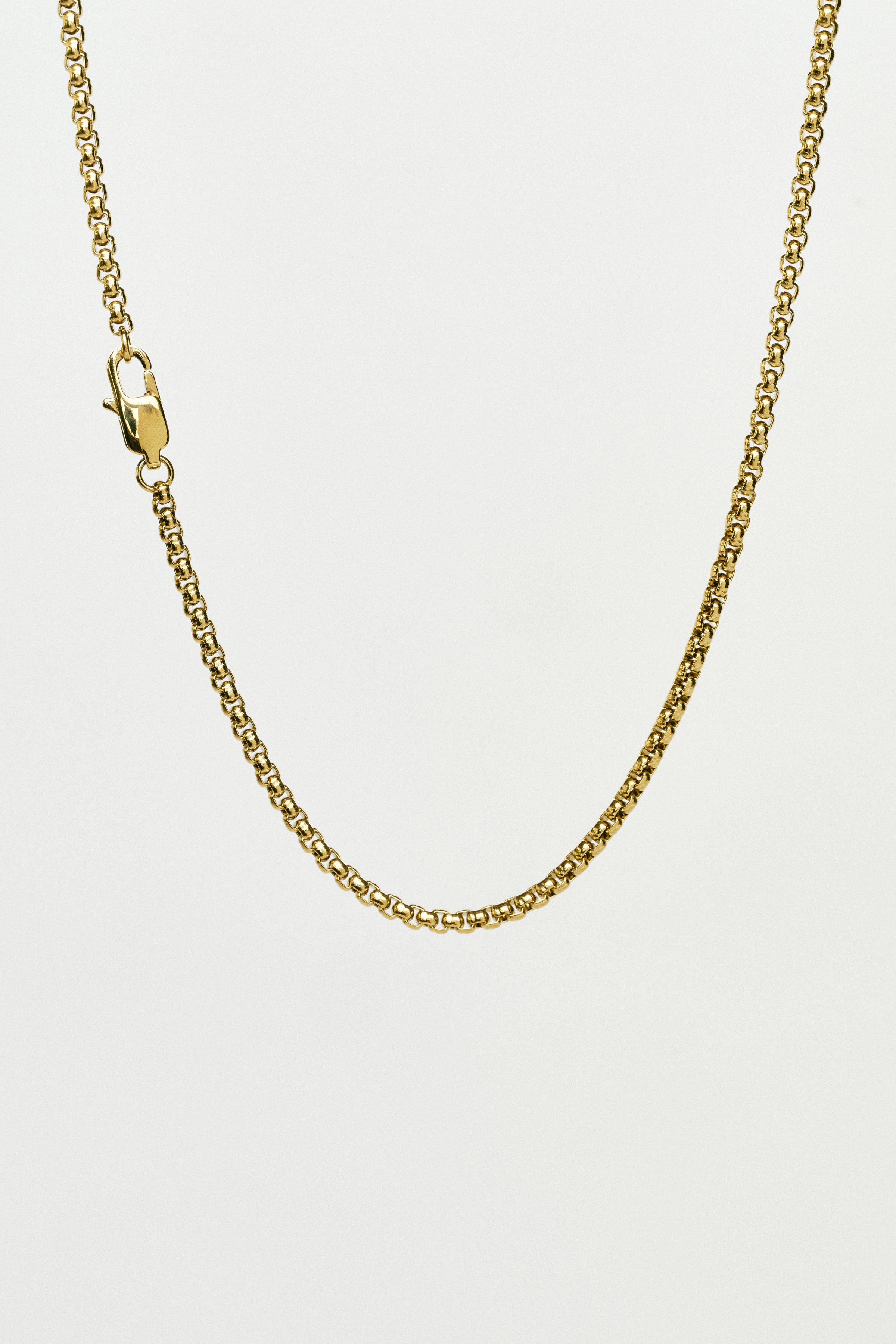 Gold chain necklace on a light grey background