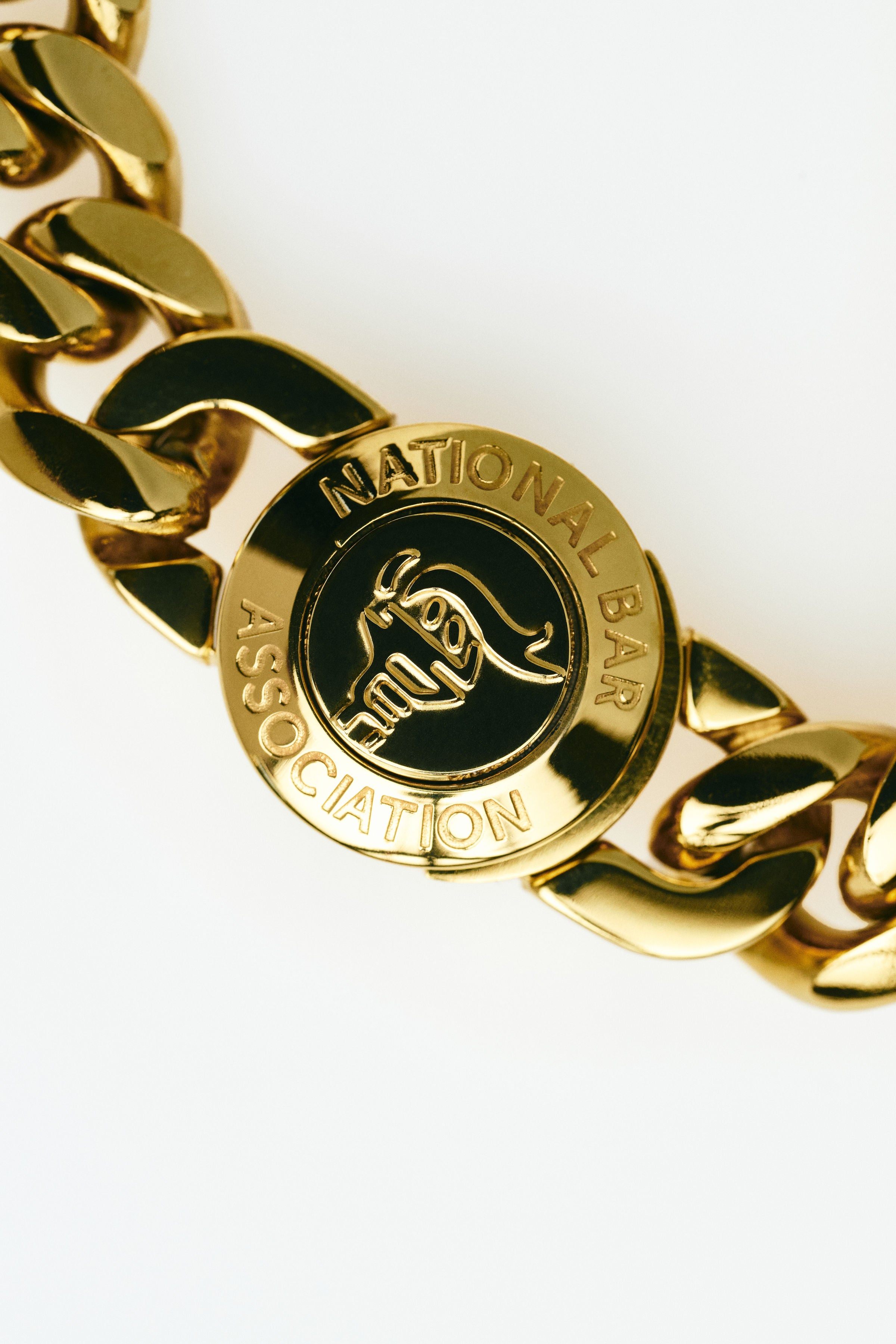 Gold chain bracelet with a National Bar Association logo on a white background