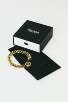 Gold chain bracelet on a black box with 'The Bar' branding on a white background