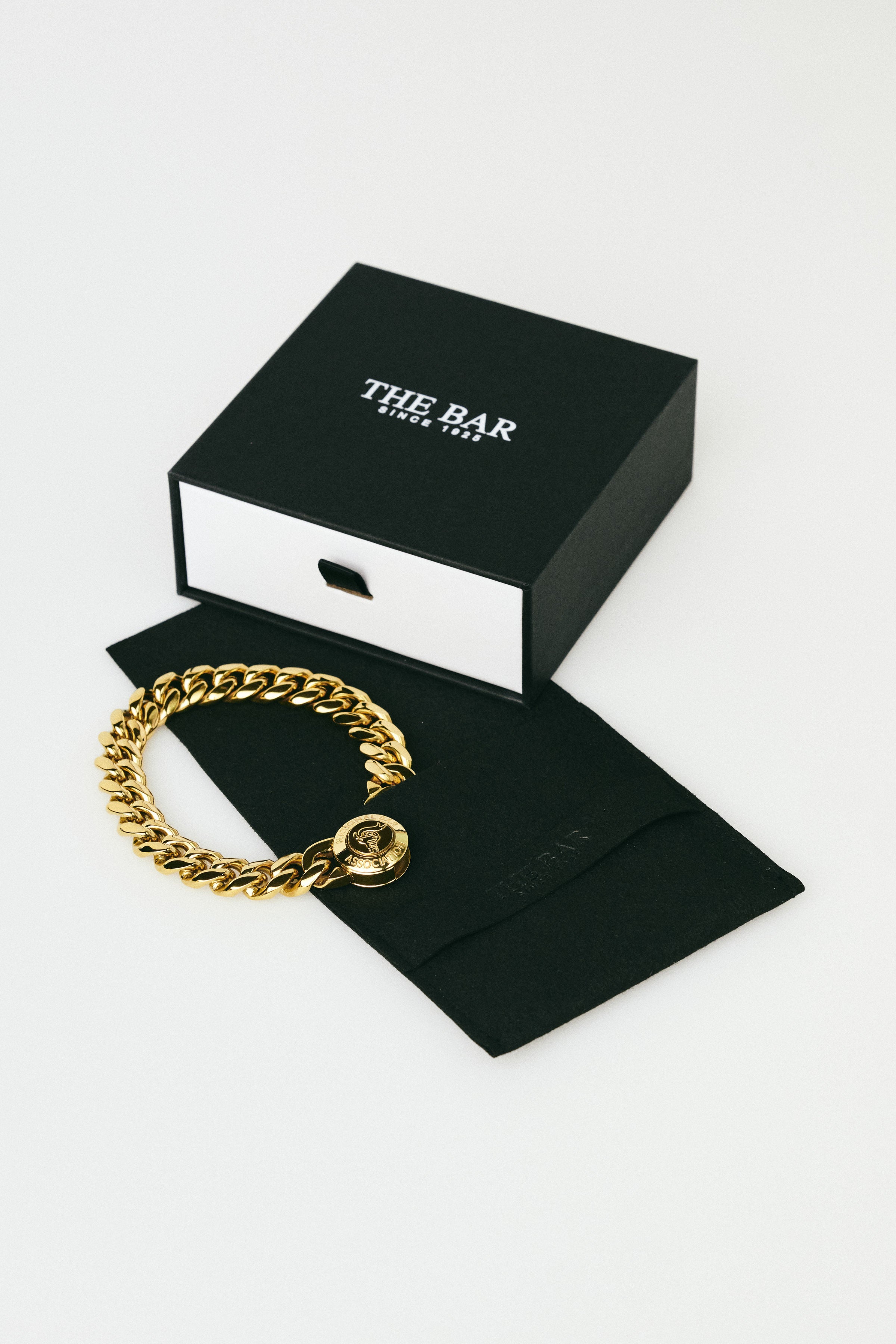 Gold chain bracelet on a black box with 'The Bar' branding on a white background