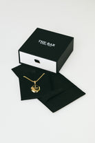 Gold necklace on black jewelry card with 'The Bar' box in the background