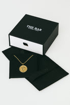 Gold necklace in a black box with 'The Bar' branding on a white background